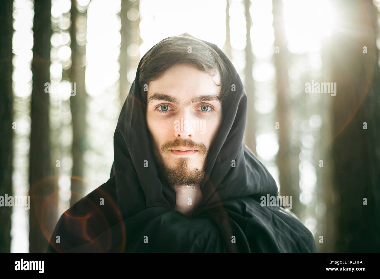Kaukasischer Mann mit Bart trägt Robe im Wald Stockfoto