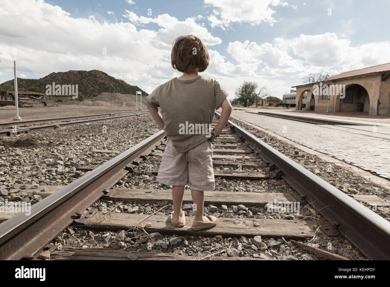 Kaukasischer Junge, der mit Händen auf Hüften auf der Bahnstrecke steht Stockfoto