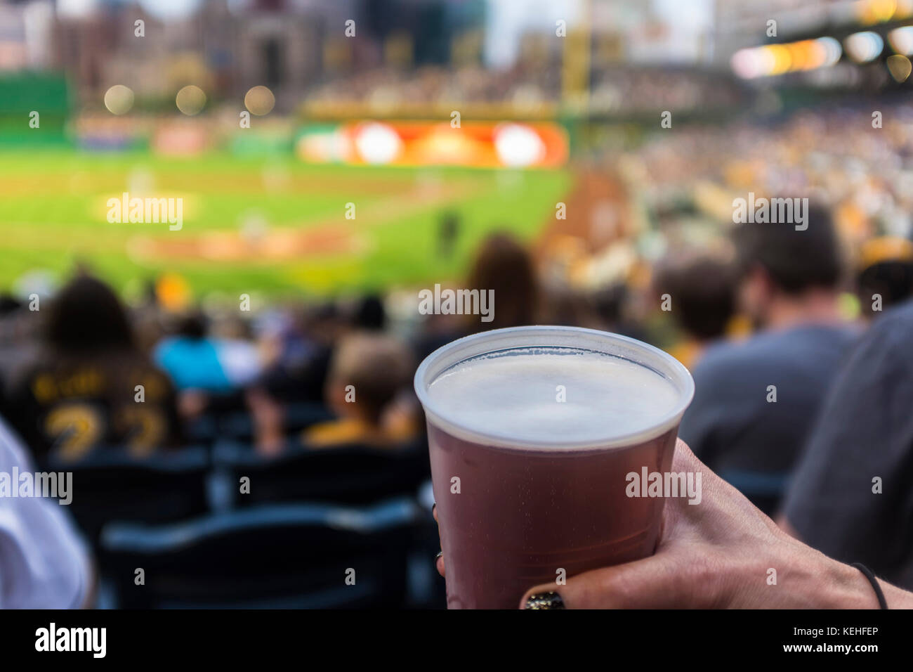 Hand der Frau, die eine Tasse Bier im Baseballstadion hält Stockfoto