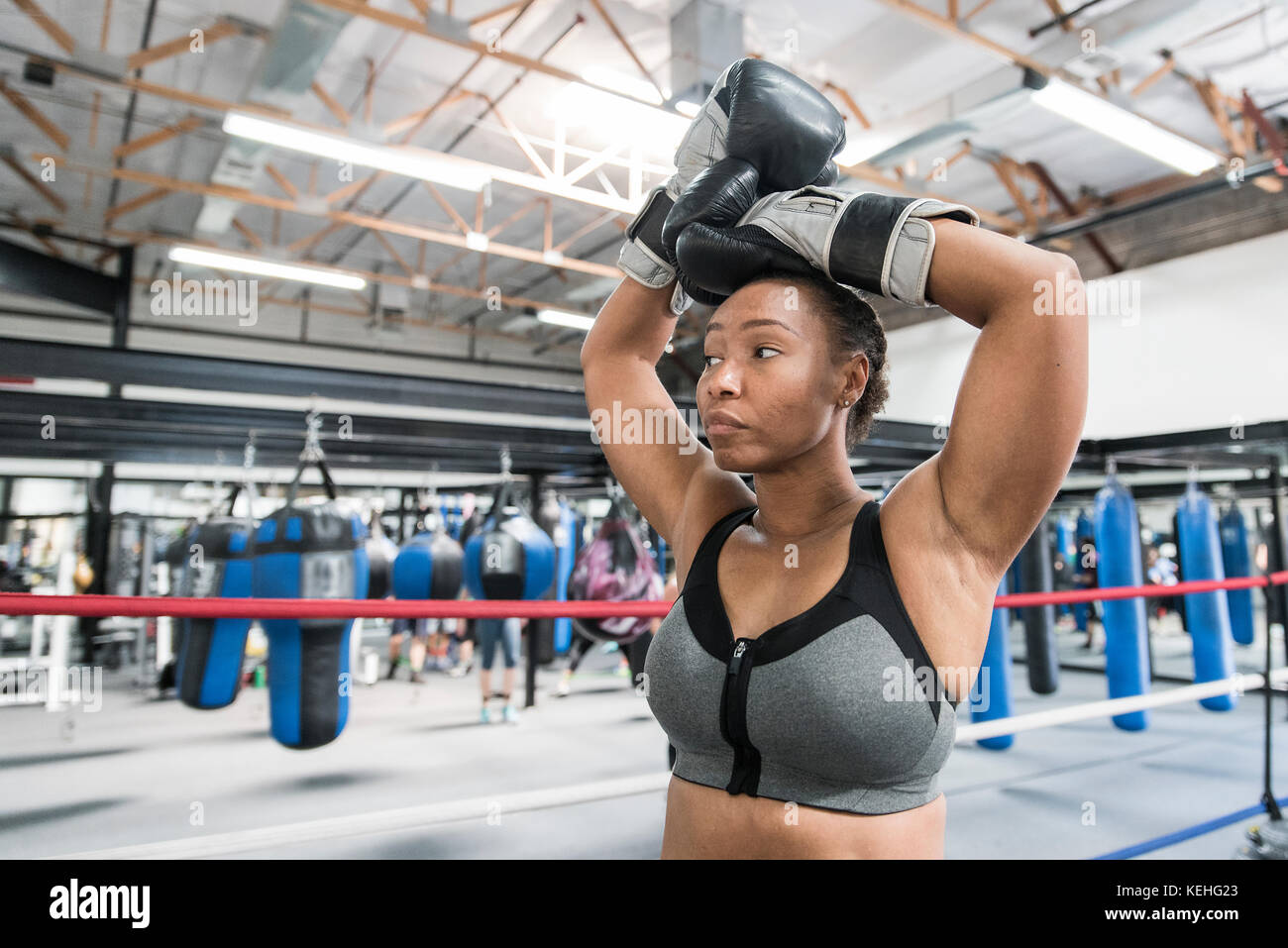 Schwarze Frau, die mit erhobenen Armen im Boxring ruht Stockfoto