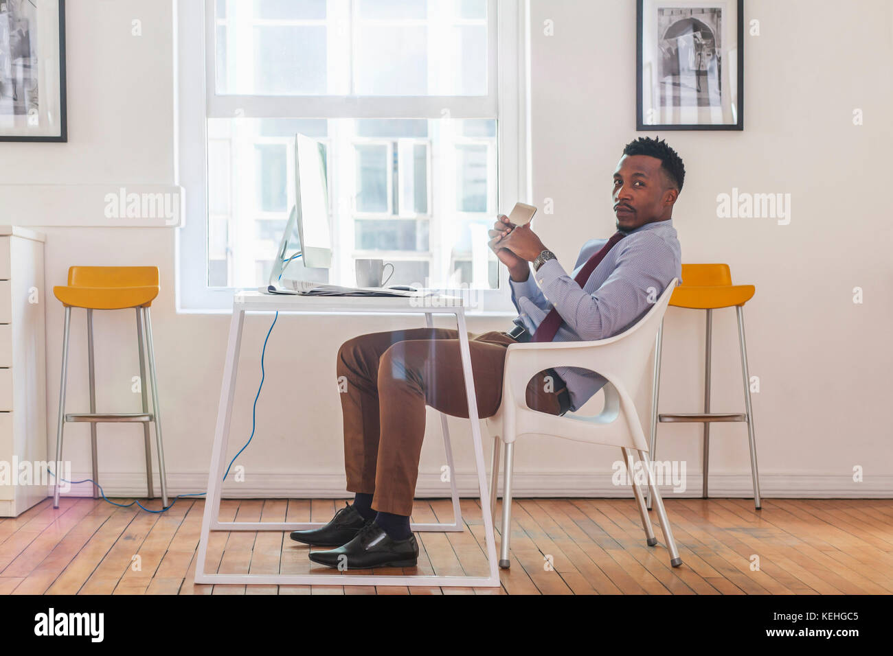 Serious Black Geschäftsmann posiert am Computer Schreibtisch Stockfoto