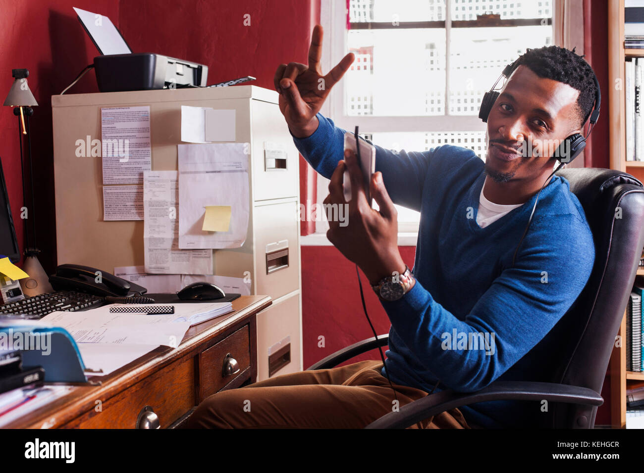 Schwarzer Mann hört mit Kopfhörern Handy Stockfoto