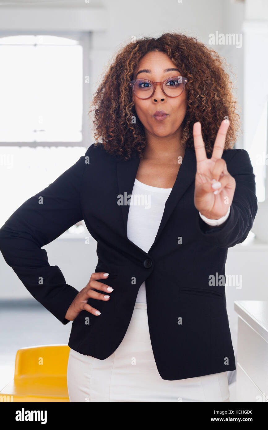 Mischlingsfrau gestikuliert Frieden in Galerie Stockfoto