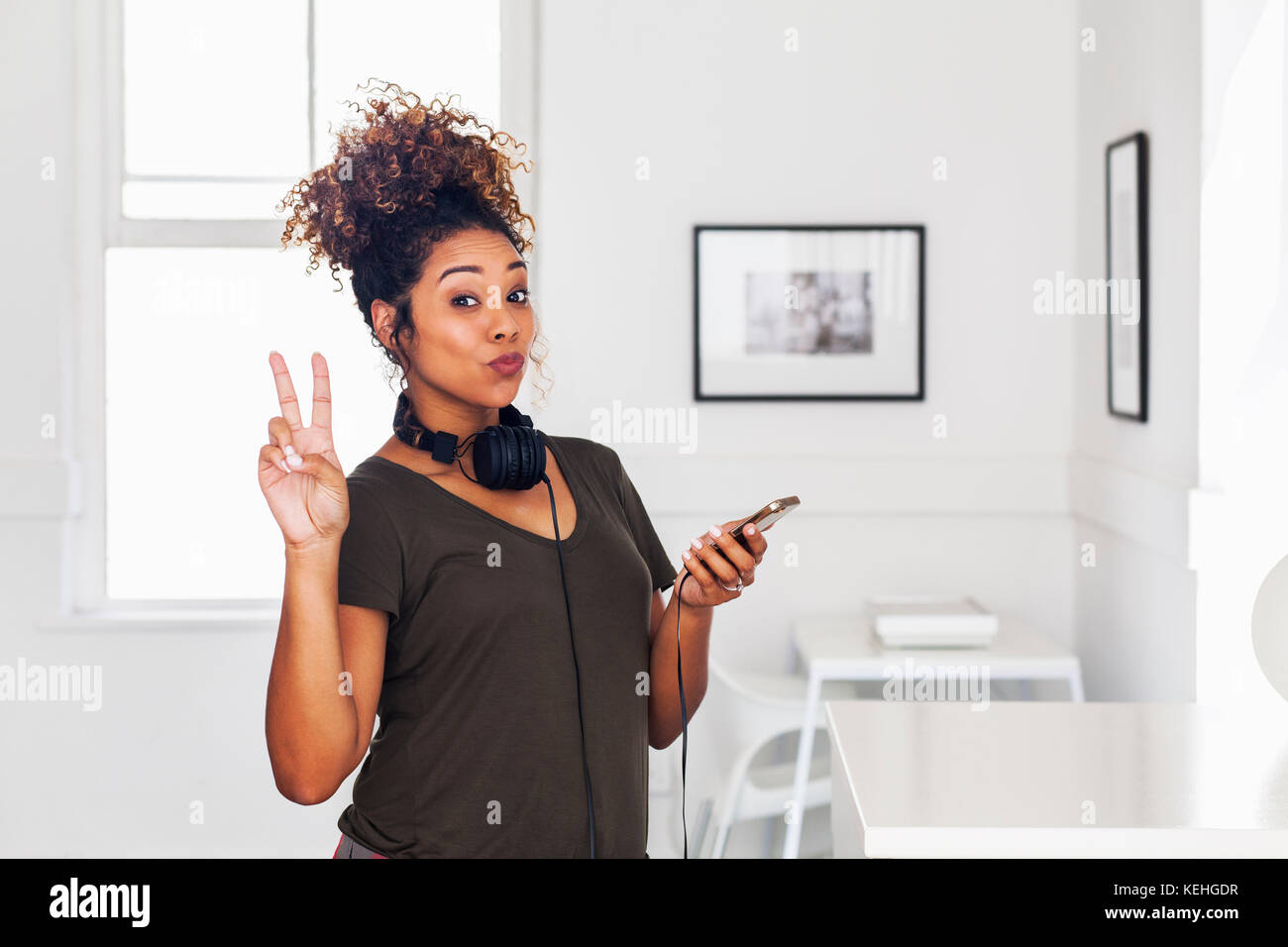 Gemischte Rasse Frau hält Handy gestikulierenden Frieden Stockfoto