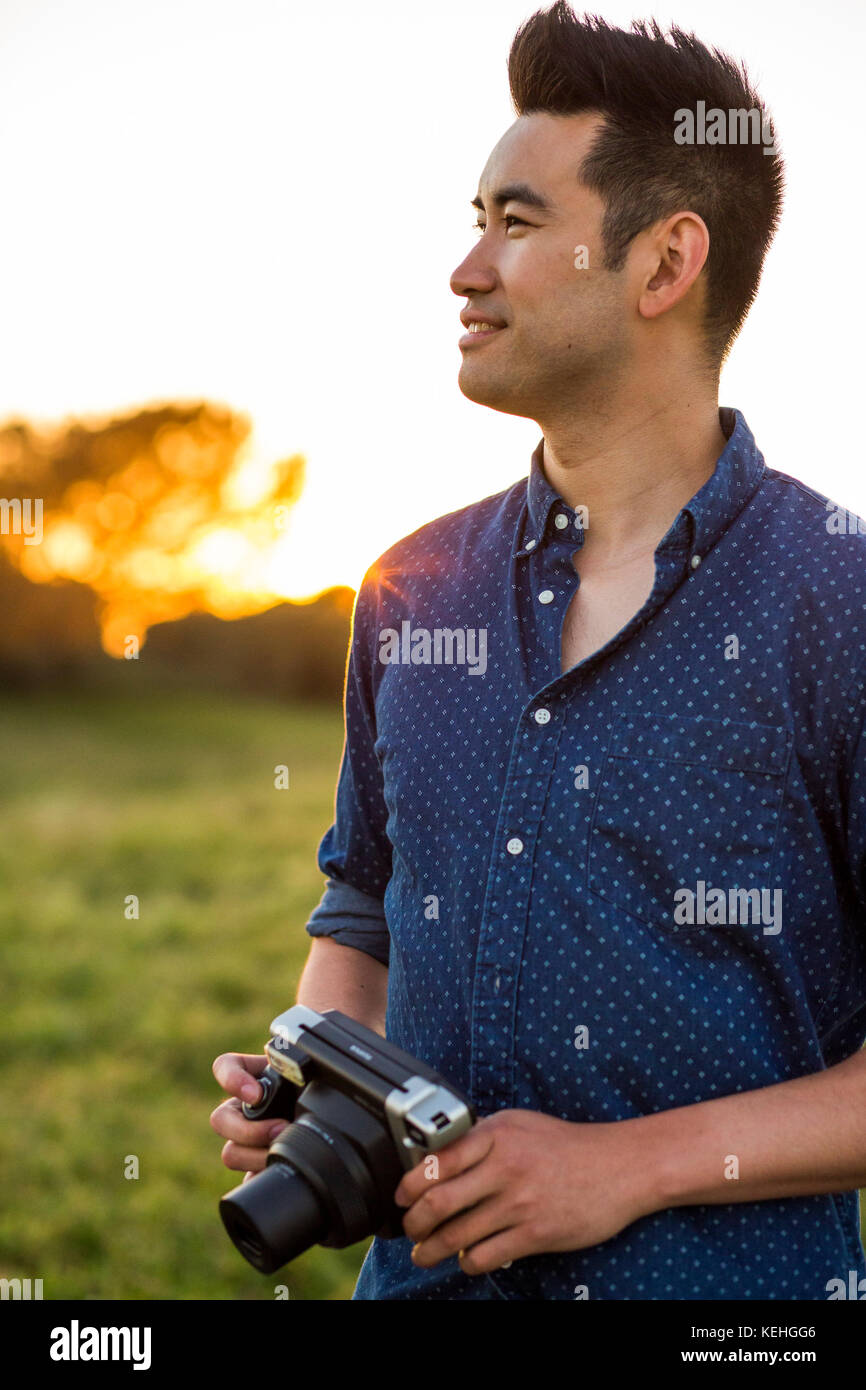 Lächelnder Chinese mit Kamera im Feld Stockfoto