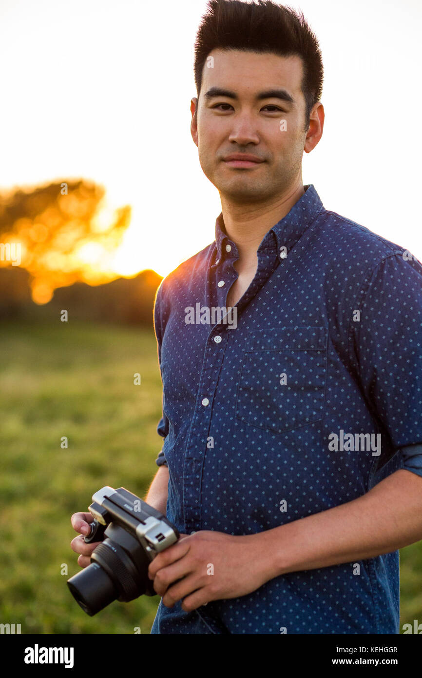 Lächelnder Chinese mit Kamera im Feld Stockfoto