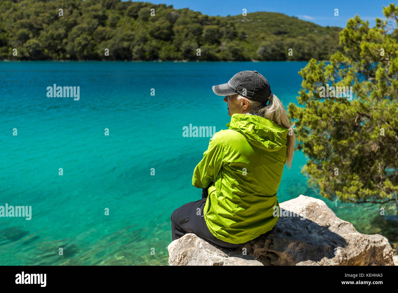Kaukasische Frau sitzt auf Felsen am See Stockfoto