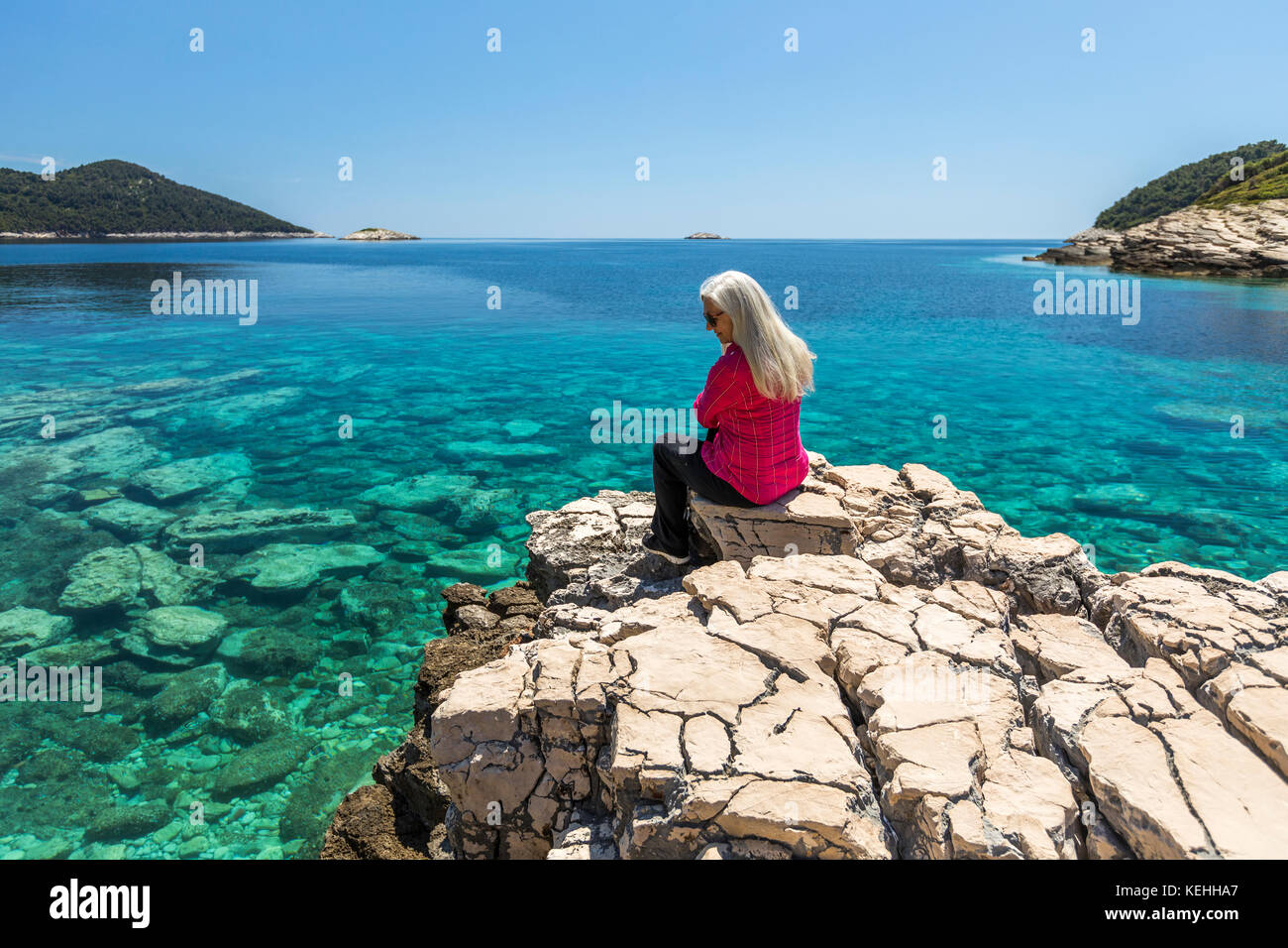 Kaukasische Frau sitzt auf Felsen See bewundern Stockfoto