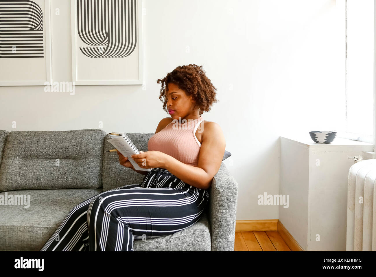 Gemischte Rasse Frau lesen Notebook auf Sofa Stockfoto