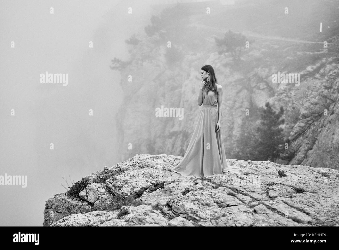 Frau trägt Kleid auf Stein im Nebel stehen Stockfoto