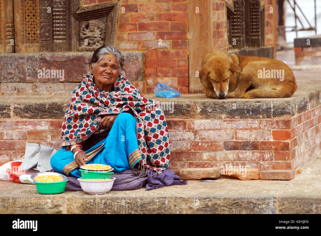 Alte nepalesische Frau verkaufen Mais die Tauben am Durbar Square, Kathmandu zu füttern. Stockfoto