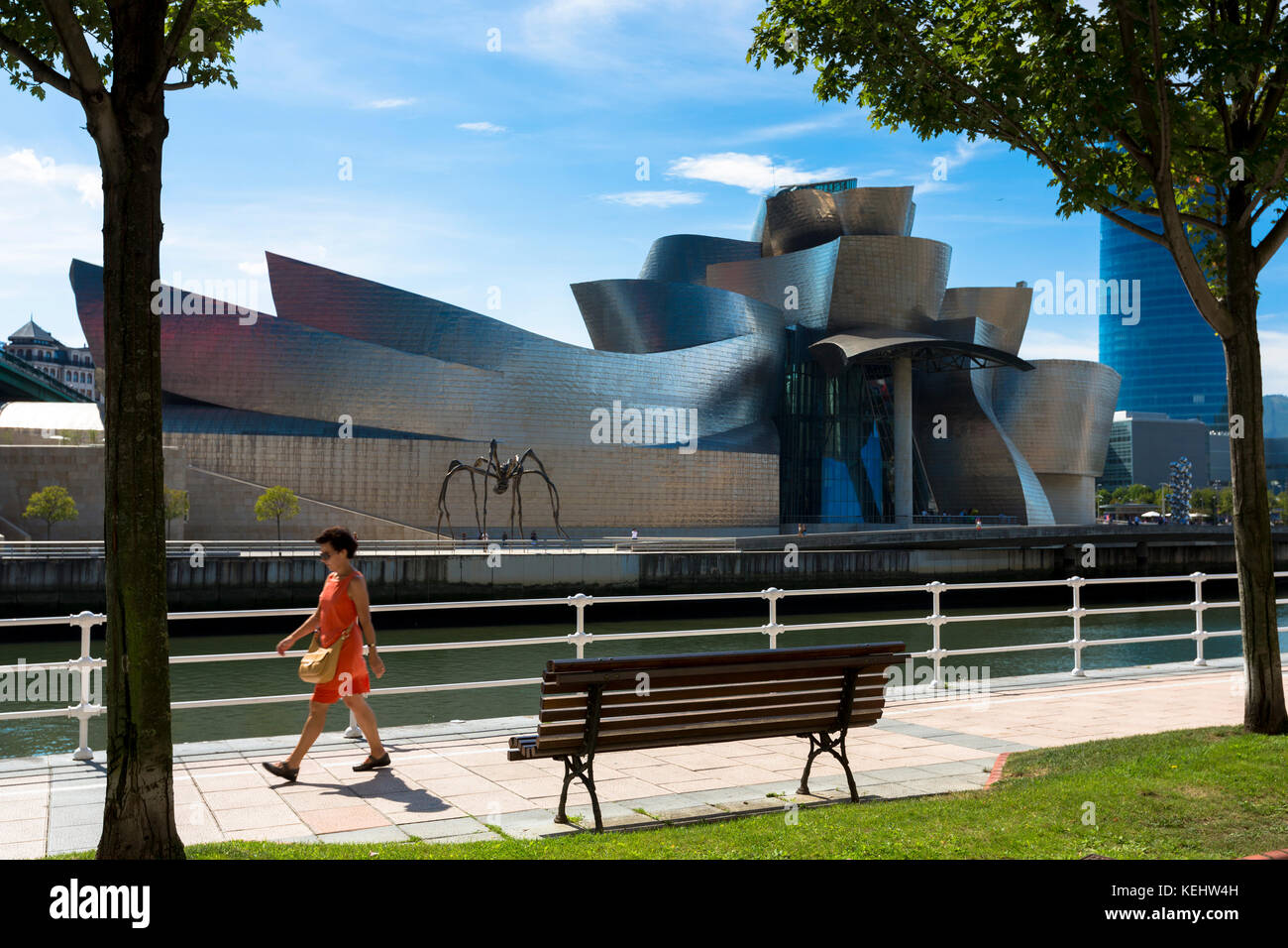 Frau geht am Guggenheim-Museum des Architekten Frank Gehry vorbei, über den Fluss Nervion in Bilbao, Baskenland, Spanien Stockfoto