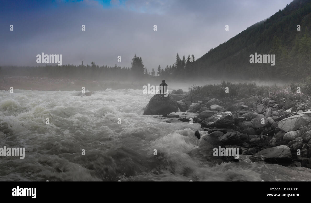 Die Silhouette eines Mannes, der in der Finsternis der Nacht Fotografie. dichter Nebel über dem Fluss Stockfoto