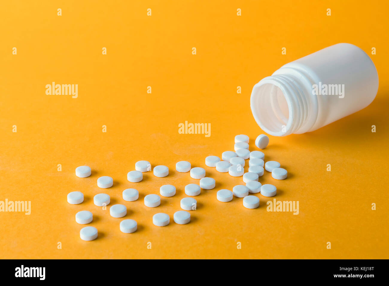 Pillen Verschütten von einer geöffneten Flasche auf orange Hintergrund isoliert Stockfoto