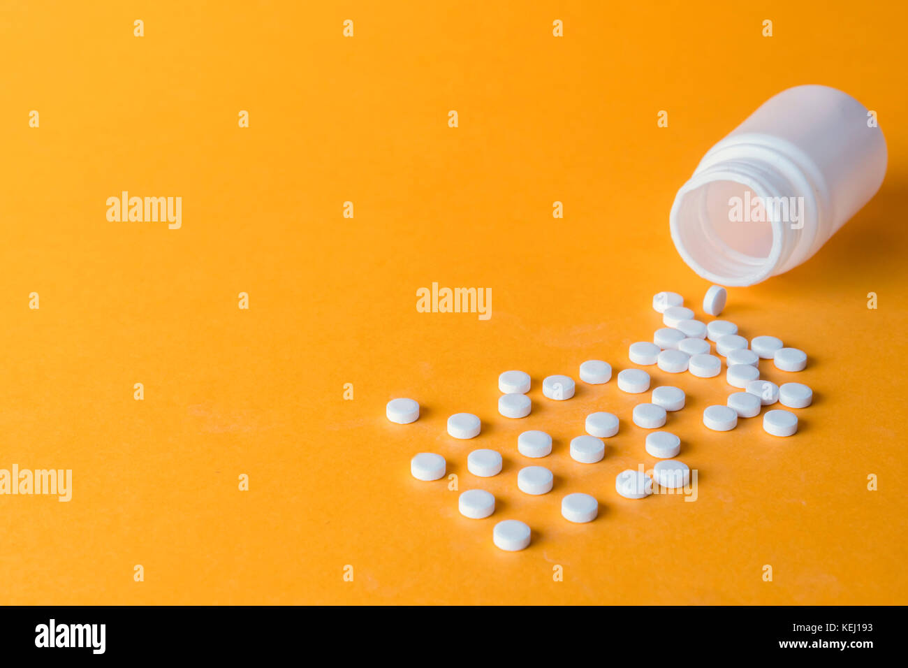 Pillen Verschütten von einer geöffneten Flasche auf orange Hintergrund isoliert Stockfoto