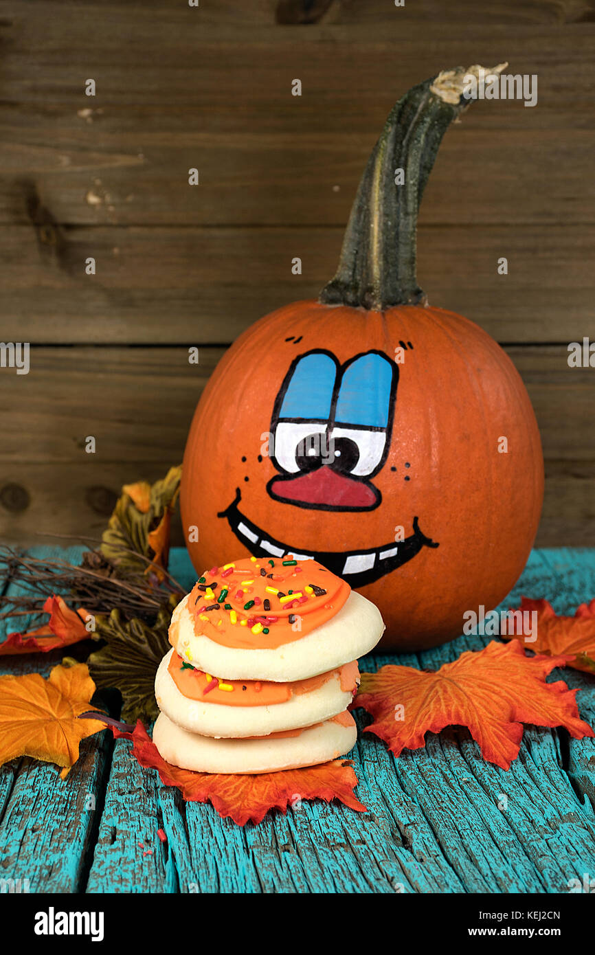 Halloween Kürbis mit Sugar Cookies auf Herbst Blätter und rustikalem Holz Stockfoto