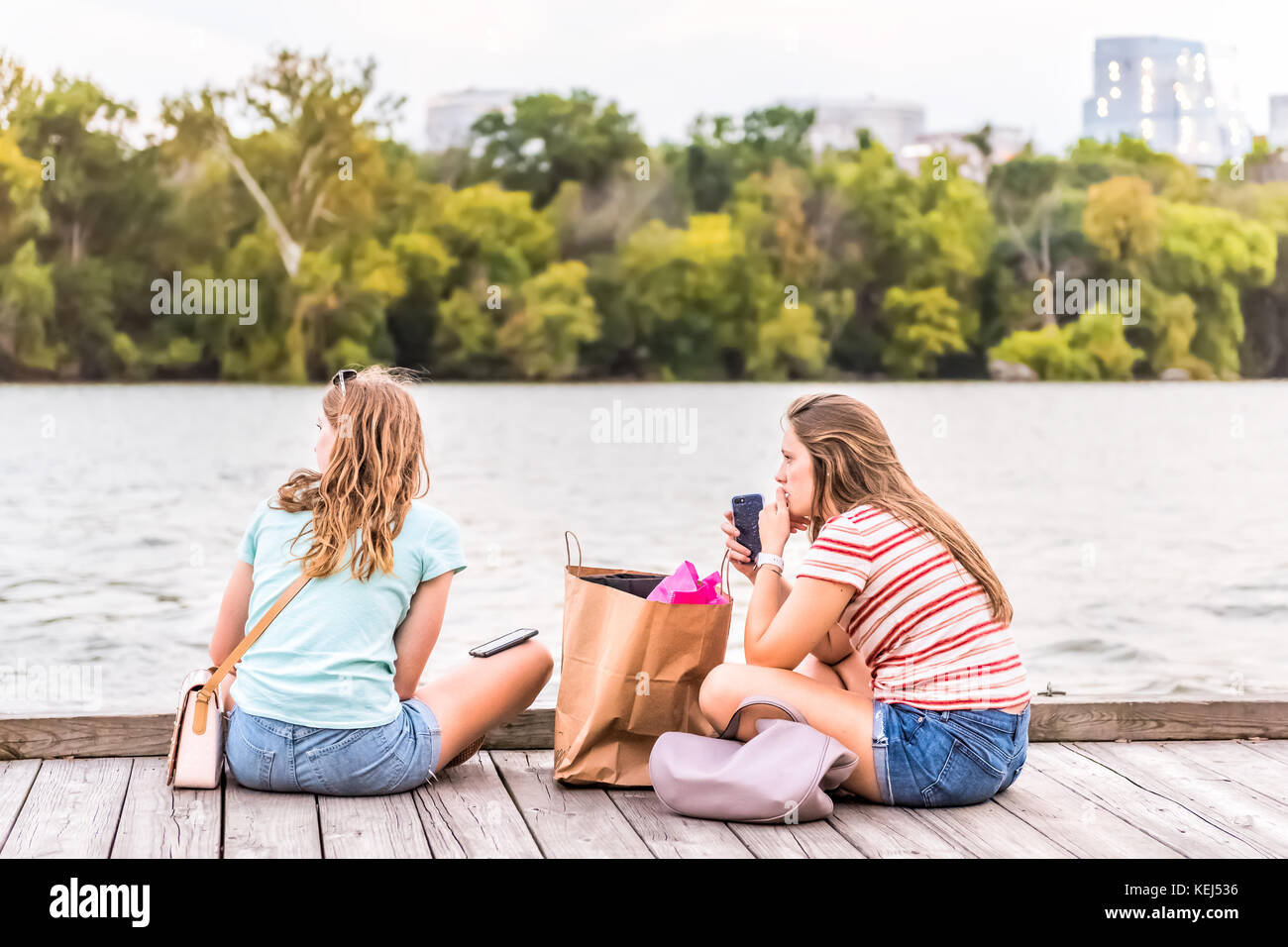 Washington DC, USA - August 4, 2017: Zwei Freundinnen Studenten in Georgetown Park Hafen sitzen auf Riverfront in Abend mit Potomac Rive Stockfoto