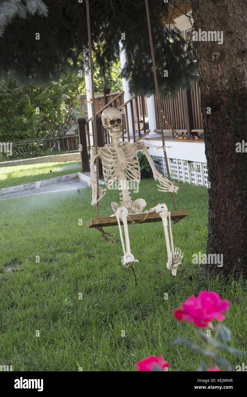Skelett auf einer Schaukel in einem Vorgarten während der Halloween-Seson in Brooklyn, NY. Stockfoto