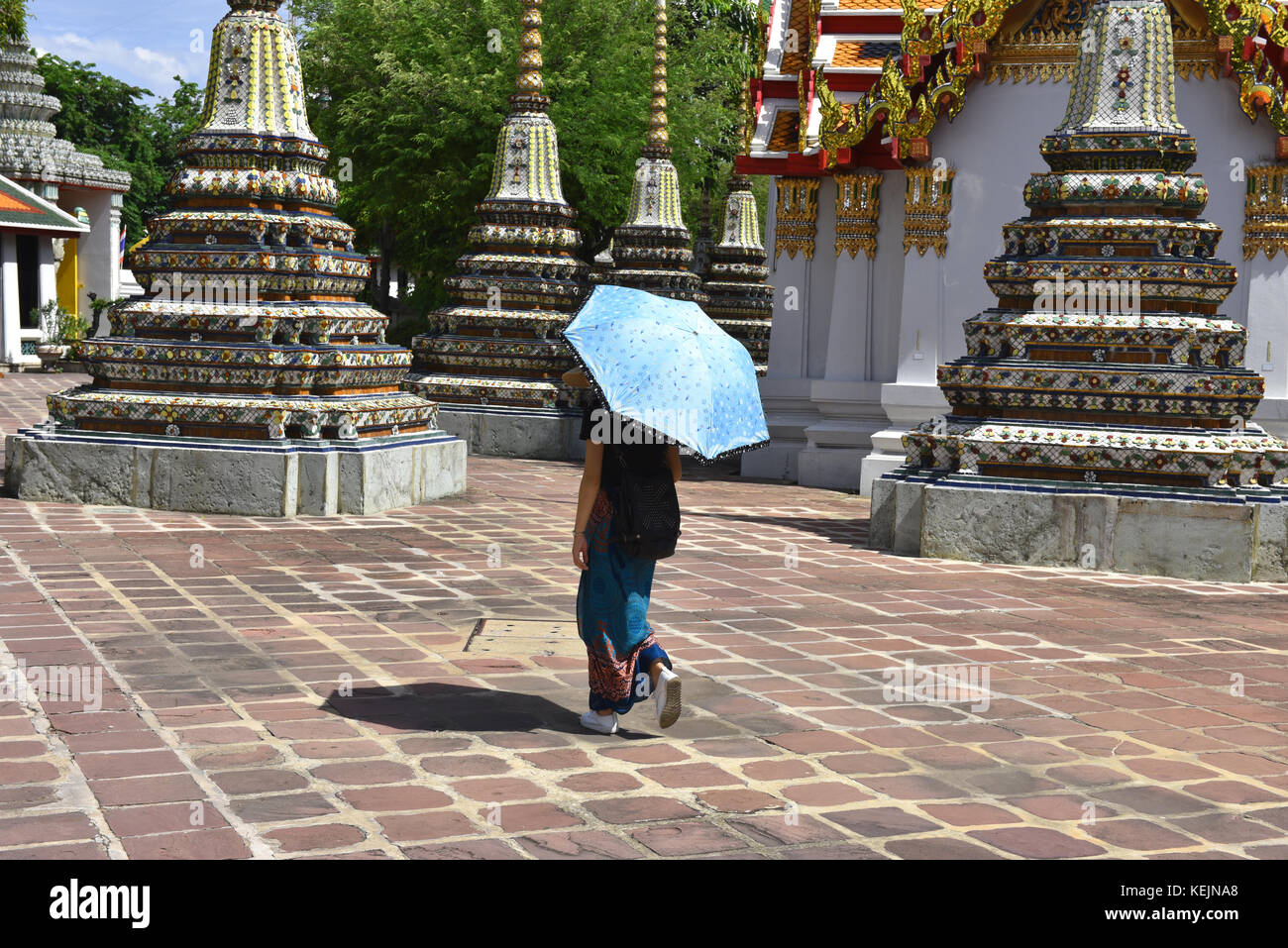 Junge Frau nimmt Schatten unter einem Sonnenschirm, wie sie durch Wat Pho Tempel Spaziergänge, in Bangkok, Thailand Stockfoto