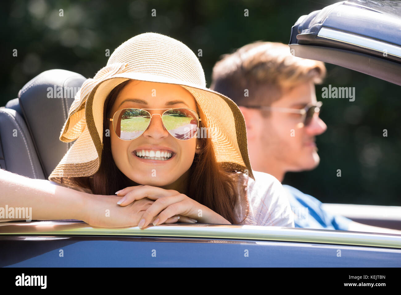 Lächelnde Frau mit Sonnenbrille genießen Fahrt in einem Auto Stockfoto