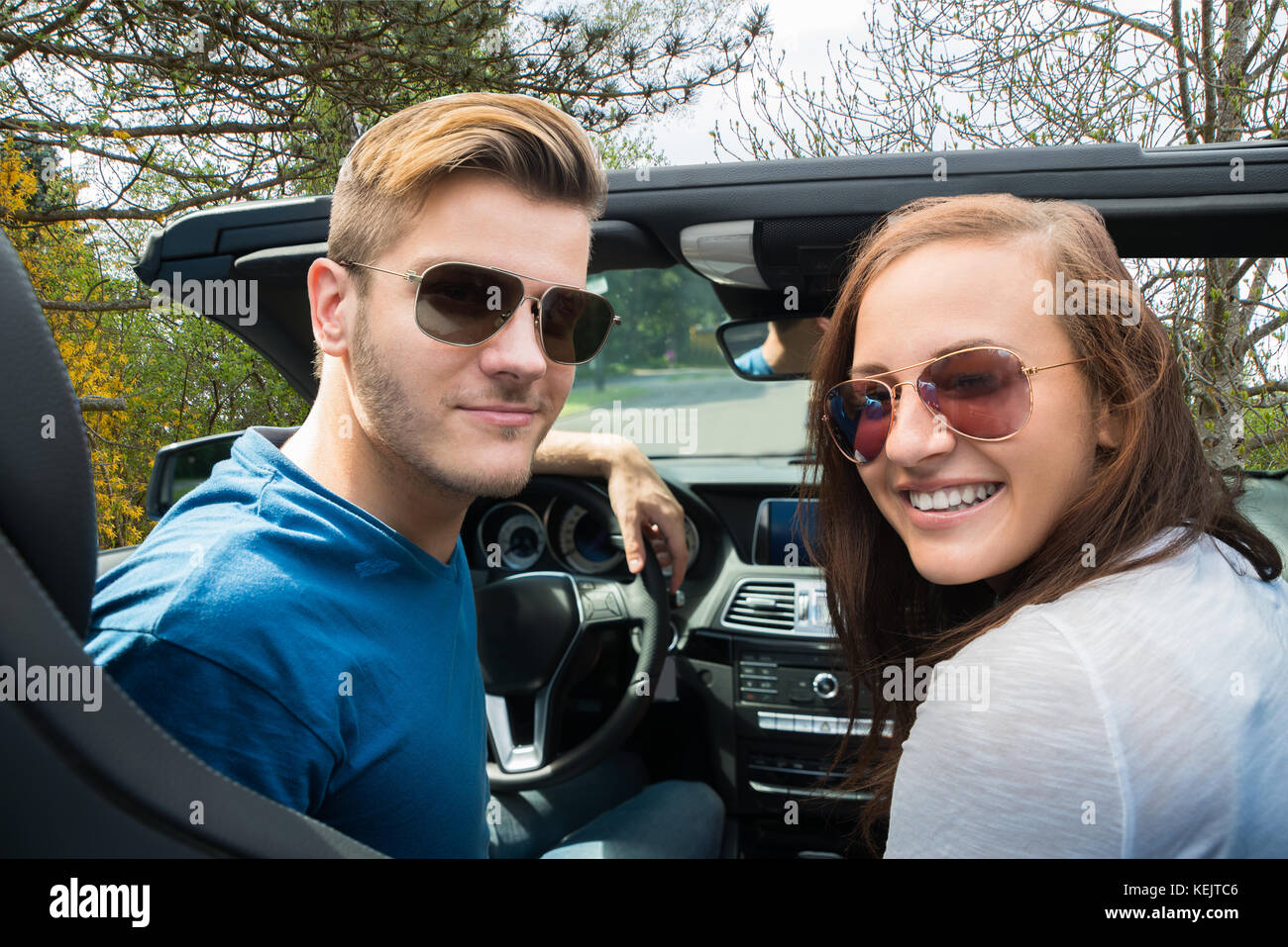 Glückliches Paar sitzen in einem Auto mit Sonnenbrille Stockfoto