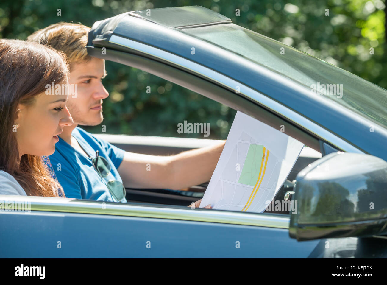 Seitenansicht einer jungen Frau auf der Suche auf Karte während der Mann Auto Stockfoto