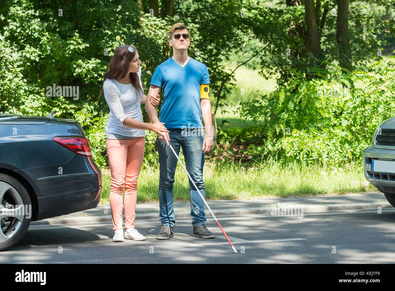 Junge Frau hilft blinden Mann mit Armband auf der Straße Stockfoto