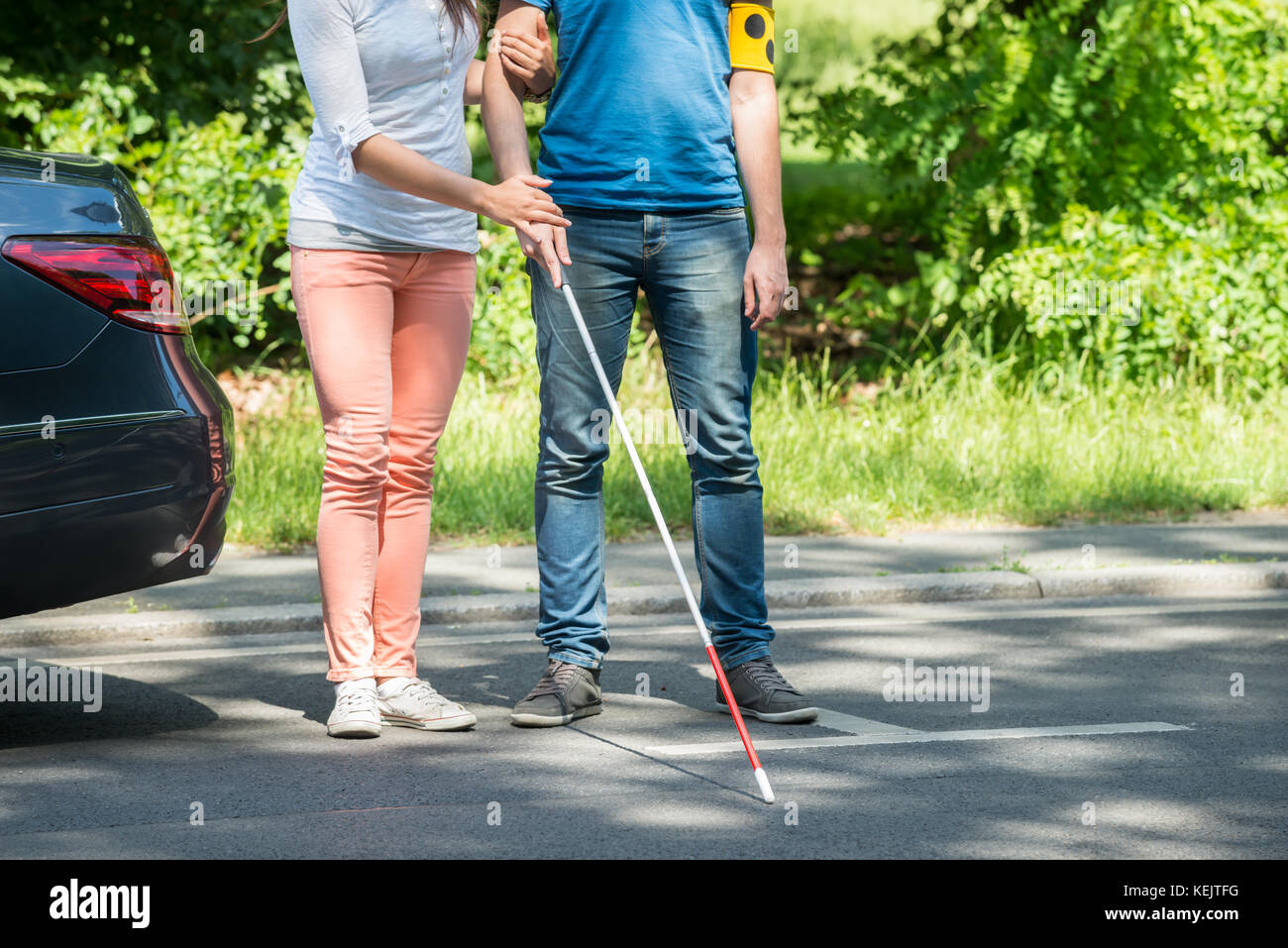 Frau Unterstützung blinder Mann mit weißem Stick auf der Straße Stockfoto