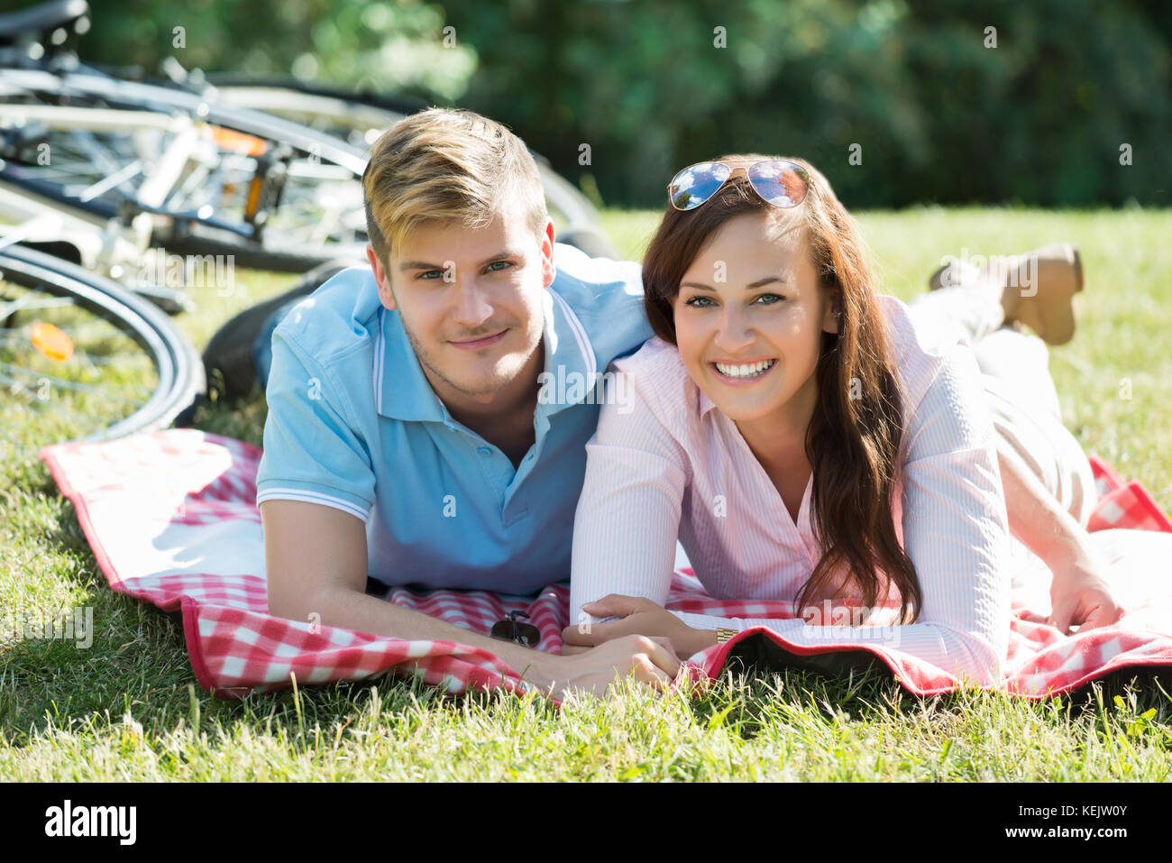 Zwei junge Glückliches Paar zur Festlegung auf grünem Gras im Park im Sommer Tag Stockfoto
