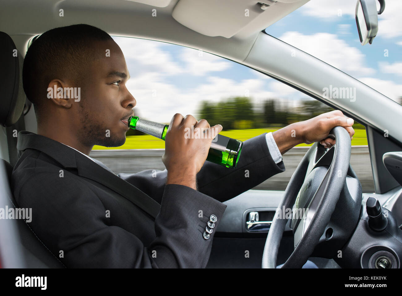 Seitenansicht eines jungen afrikanischen Geschäftsmann Bier trinken während der Fahrt Auto Stockfoto