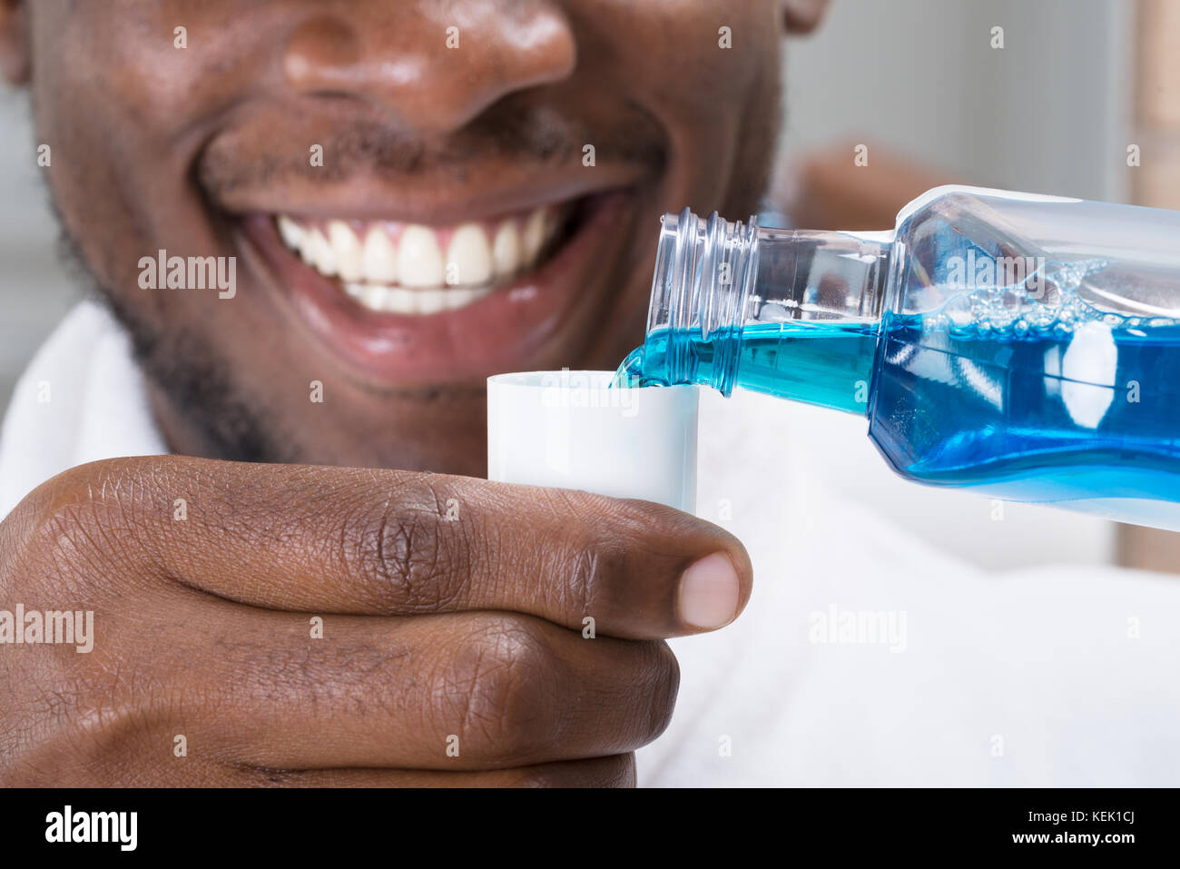 Close-up mit einem lächelnden afrikanischer Mann Gießen Mundwasser in die Kappe Stockfoto