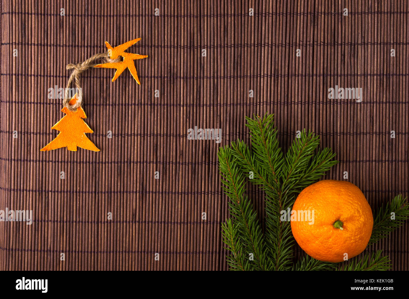 Neues Jahr Konzept. weihnachtsdekorationen Hand von Tangerine peel- und Tannenholz Äste auf Bambus matte Hintergrund Stockfoto