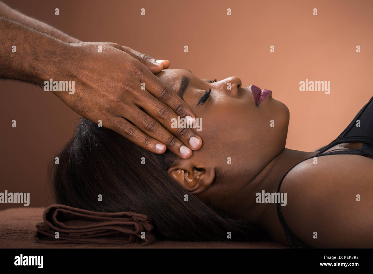 Entspannt Junge afrikanische Frauen, die Stirn Massage im Spa Stockfoto