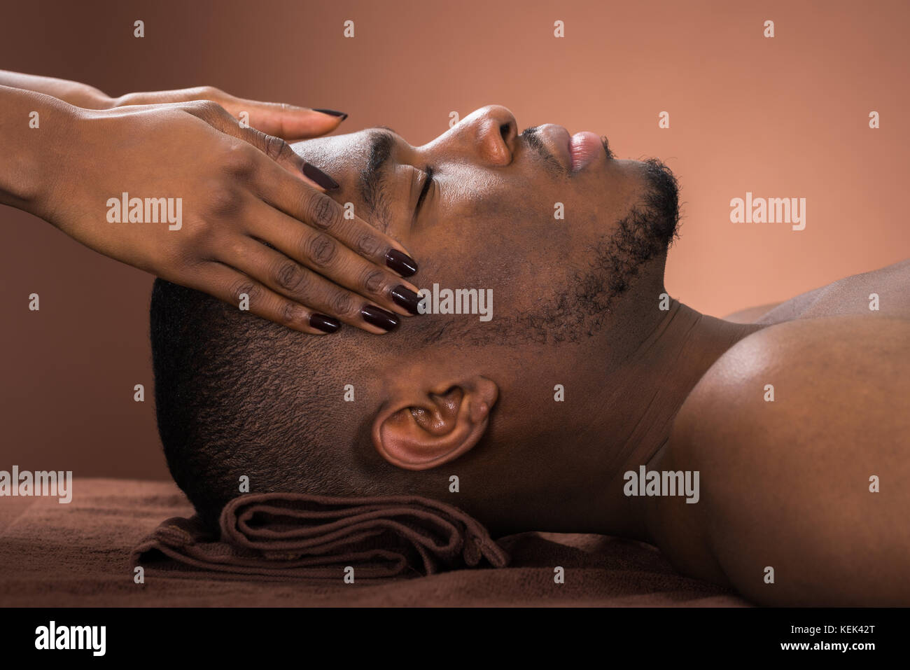 Junge afrikanische Mann die Stirn Massage im Spa Stockfoto