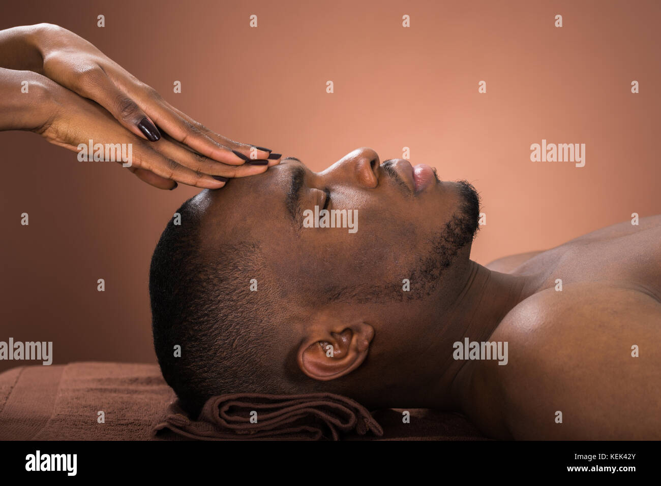 Junge afrikanische Mann die Stirn Massage im Spa Stockfoto