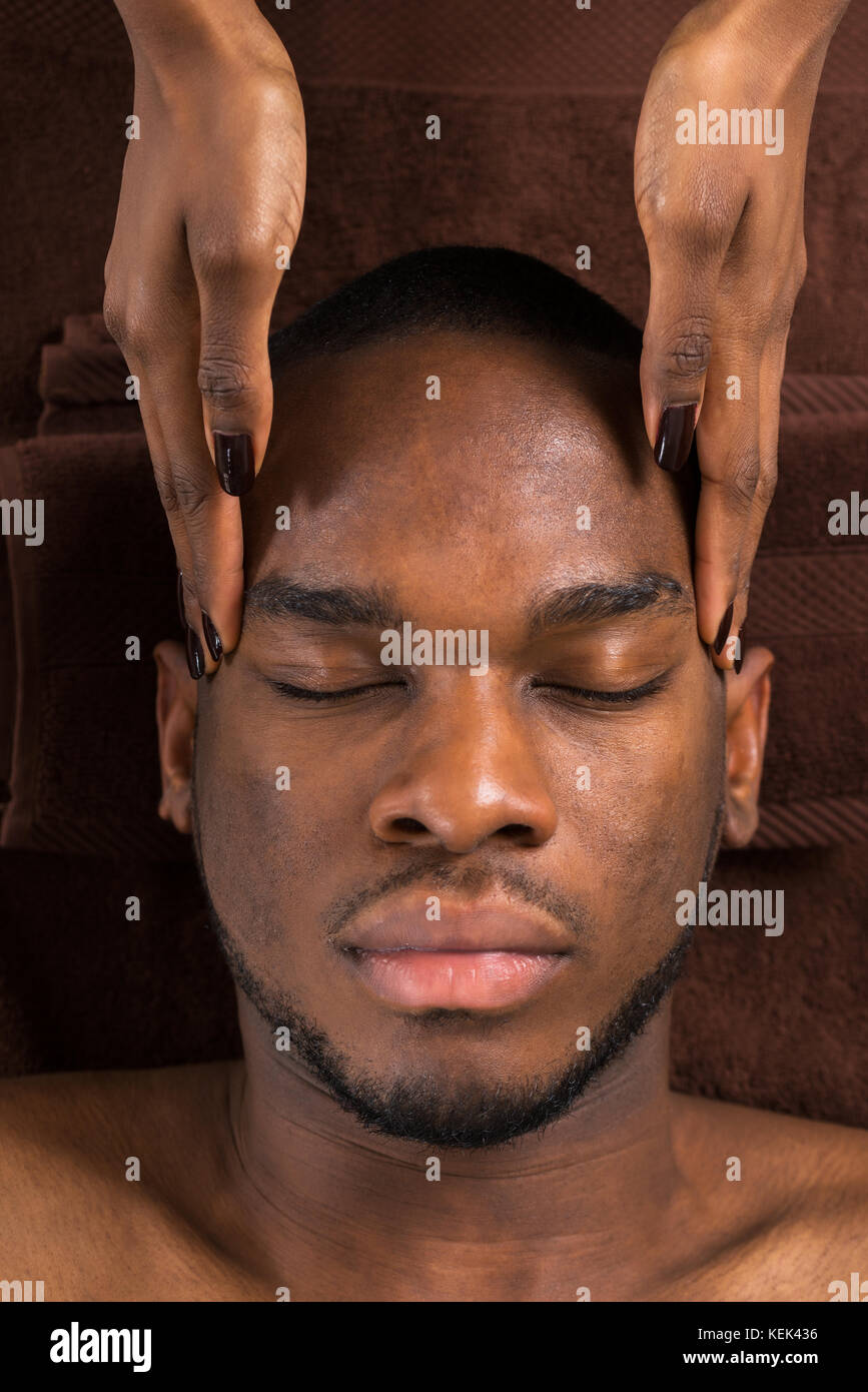 Nahaufnahme der jungen afrikanischen Mann, Stirn Massage im Spa Stockfoto