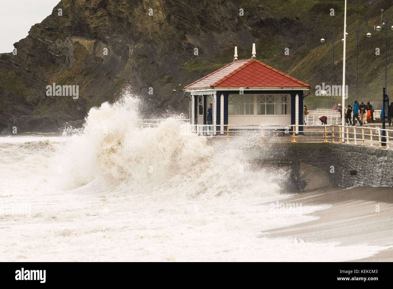 Aberystwyth, Wales, UK. 22. Oktober 2017. Am Tag nach aberystwyth nahm ein Zerschlagen von Sturm Brian. Ein Mann flüchtet sich in der promenade Tierheim als eine Welle gegen die Promenade Wand stürzt. Credit: Alan Hale/alamy leben Nachrichten Stockfoto
