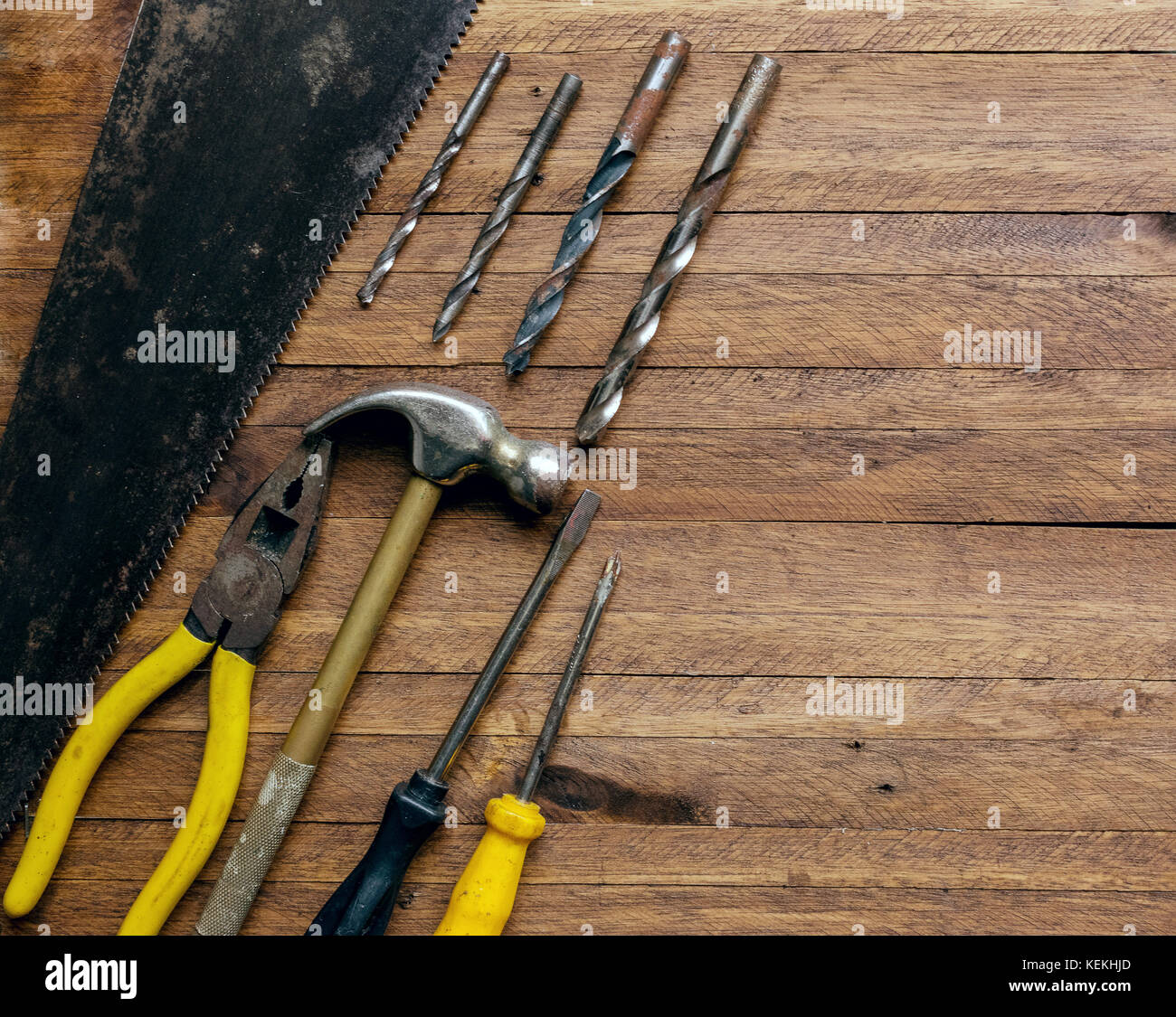 Rostig und Alt verwendet Zimmerei und Garage Tools auf einem hellen braun Holz Hintergrund, zeigt vielfältige Werkzeuge, Zangen und sah mit Metall, Metall Bohrer, Hammer Stockfoto