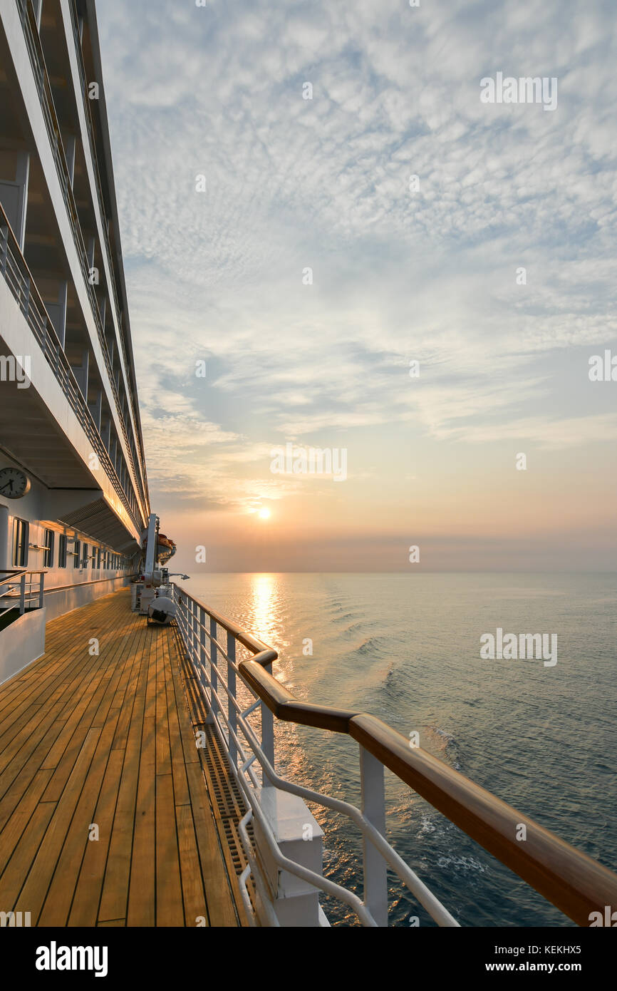 Kreuzfahrtschiff hölzerne Promenade Deck mit schönen Sonnenuntergang und Reflexion auf dem Ozean. Stockfoto