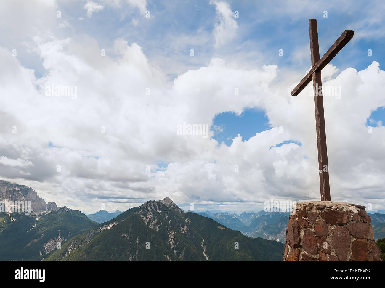 Kreuz aus Holz auf dem Gipfel des Berges. Berglandschaft über den Wolken. Kreuz auf der Spitze eines Berges, wie üblich in den Alpen. Stockfoto