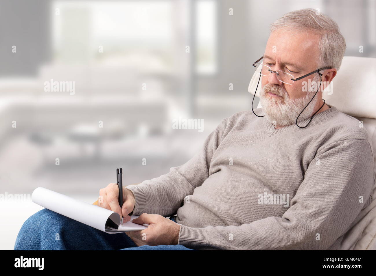 Alter Mann eine Einkaufsliste mit einem Stift auf Papier für den Urlaub Stockfoto