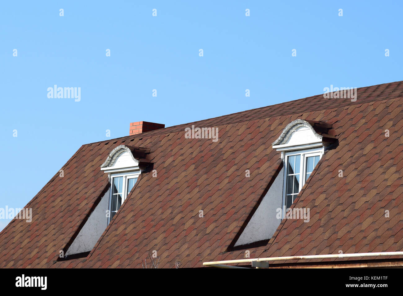 Ein Haus mit einem Dach aus Blech. das Haus mit Giebeln, Fenstern und Dach, ausgestattet mit Überlauf und Schutz vor Schnee. Stockfoto