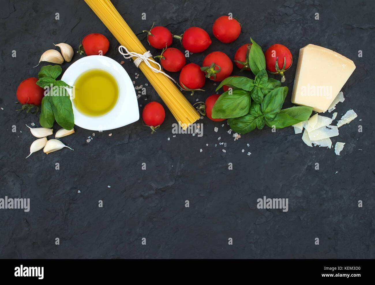 Zutaten zum Kochen Pasta Spaghetti, Olivenöl, Knoblauch, Parmesan, Tomaten und frischem Basilikum auf schwarzem Schiefer Hintergrund, Ansicht von oben, kopieren Raum Stockfoto