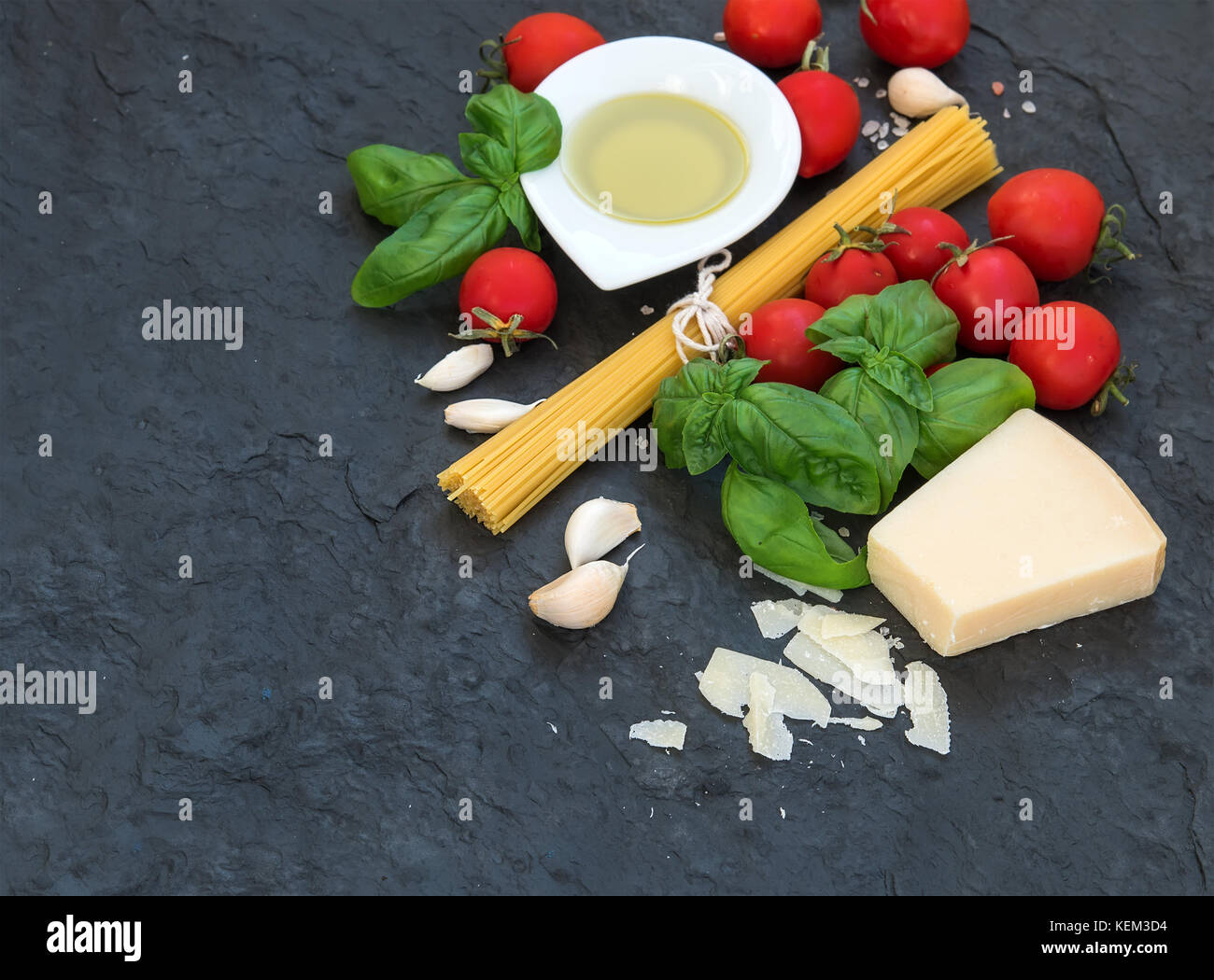Zutaten zum Kochen Pasta Spaghetti, Olivenöl, Knoblauch, Parmesan, Tomaten und frischem Basilikum auf schwarzem Schiefer Hintergrund, Ansicht von oben, kopieren Raum Stockfoto