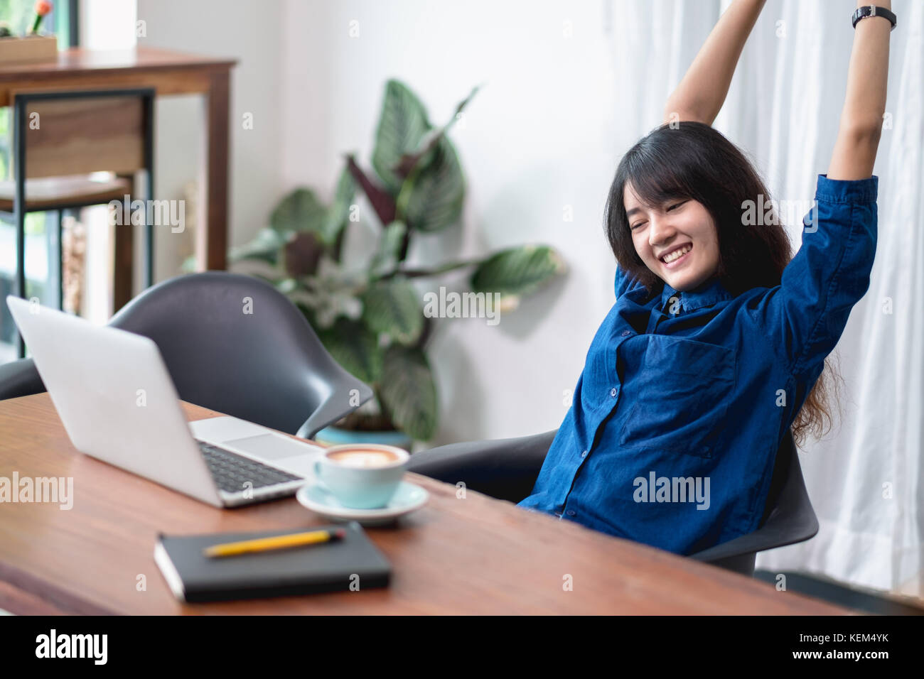 Asien Frau entspannen Sie nach der Arbeit, Frau den Arm anheben, die sich vor dem Laptop und Kaffee Tasse auf Holz Tisch im Cafe Restaurant, Lifestyle, Stockfoto