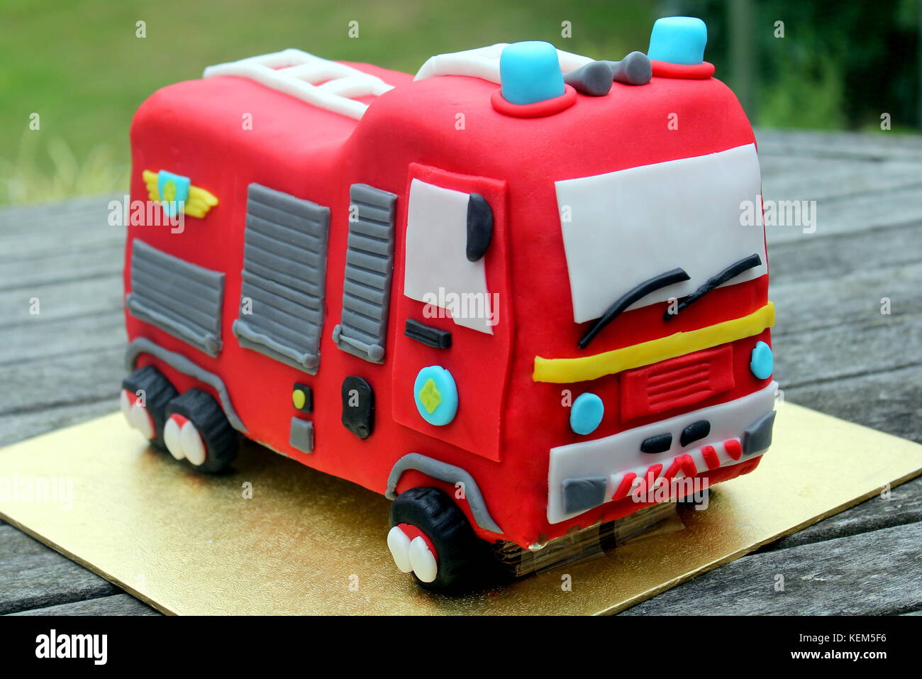 Child's hausgemachte red fire engine Geburtstag Kuchen auf einen Tisch draußen Stockfoto