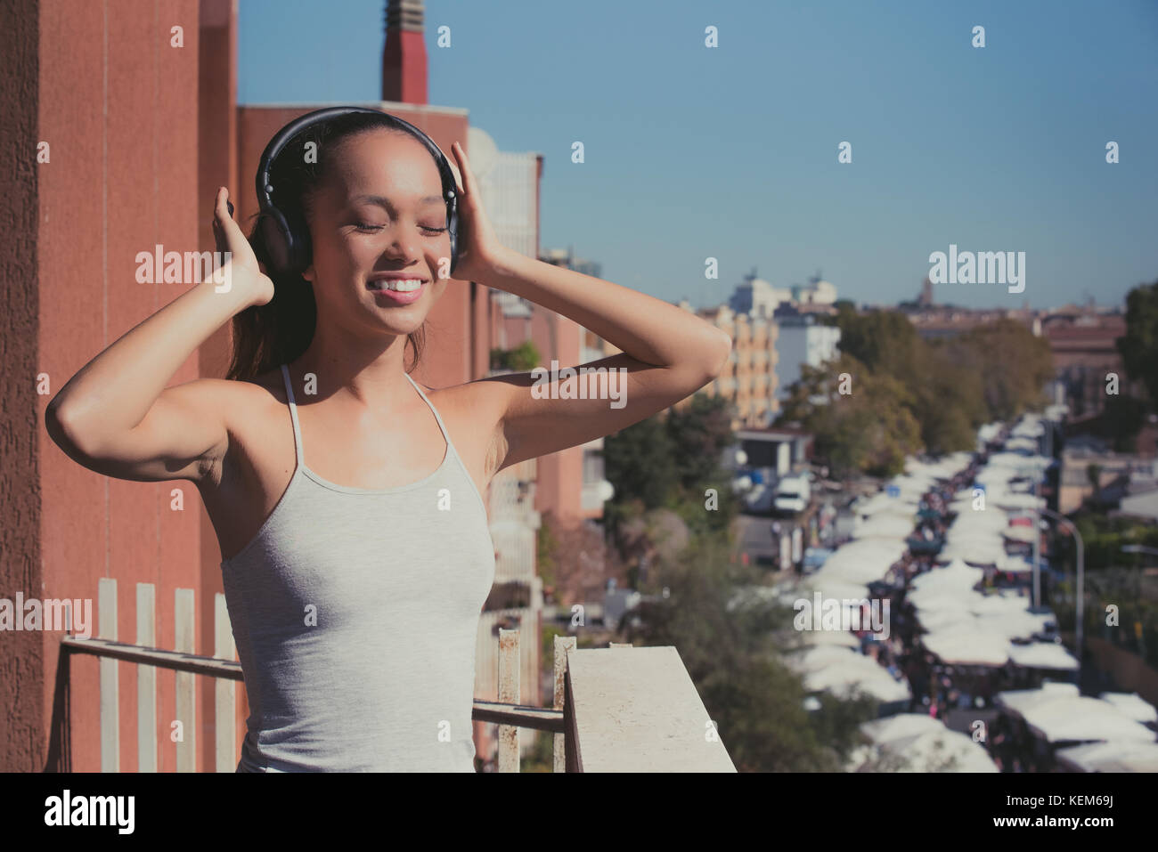 Jungen asiatischen Teenager Frau Outdoor Portrait geschlossenen Augen Sonnenlicht lächelnd mit Kopfhörer im städtischen Hintergrund Stadt Lebensstil Stockfoto