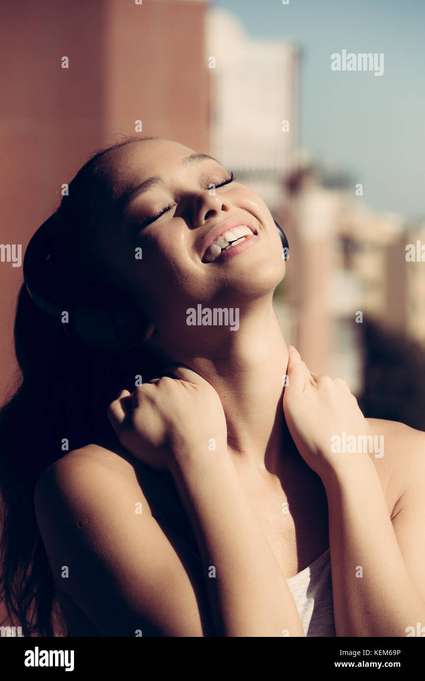 Jungen asiatischen Teenager Frau Outdoor Portrait geschlossenen Augen Sonnenlicht lächelnd mit Kopfhörer portrait Stockfoto