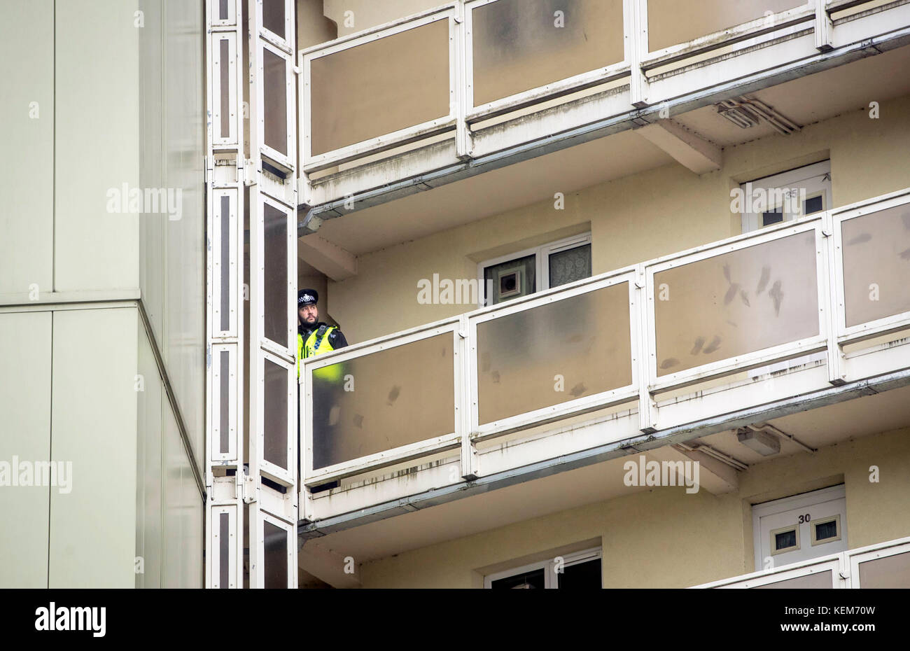 Ein Polizist auf einem Balkon in Newcastle Haus in Bradford, wo ein 18 Monate altes Baby starb nach einem Sturz aus dem sechsten Stock Fenster, eine 23-jährige Frau wurde wegen des Verdachts auf Mord in Zusammenhang mit dem Baby fallen verhaftet. Stockfoto