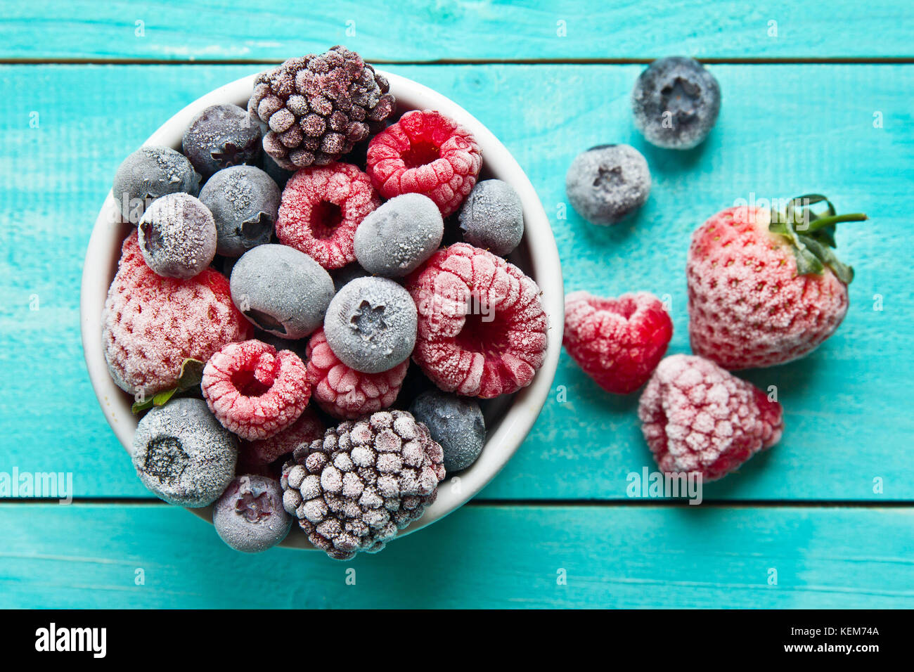 Verschiedene gemischte gefrorene Beeren in einer Schüssel auf blauem Hintergrund Stockfoto